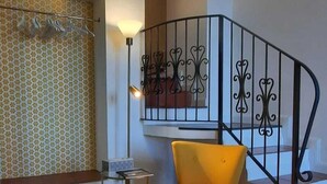 Uma escada com corrimão de metal preto, uma cadeira amarela e uma parede com padrão.