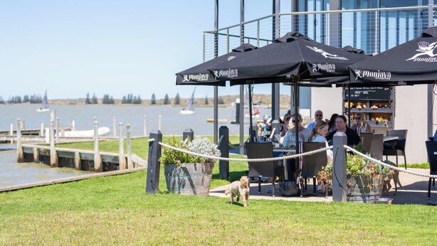 An outdoor seating area with umbrellas, a dock, and a view of the water. - Wild Rose Studio, 100M to the water (Goolwa South)