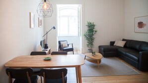 En moderne stue med et træspisebord, lædersofa i sort farve og en potteplante.