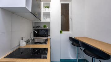 Una cocina compacta con microondas integrado, un lavamanos y una pequeña encimera.