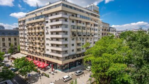 A multi-story hotel with a central courtyard, outdoor seating, and a parking area. - Metropole Apartments Studio City (Bucharest)