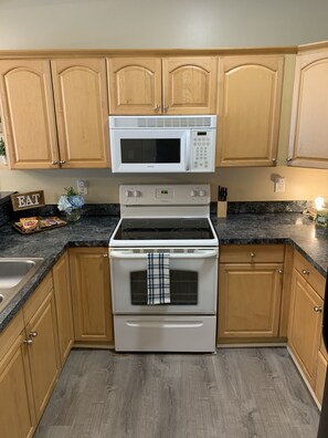 Enjoy cooking in this well-equipped kitchen with a central stove, microwave, and stainless steel sink.