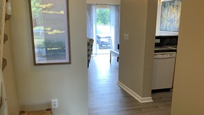 A hallway with a woven bench, a dining area with a table and chairs, and a kitchen with a dishwasher. - 2 Story Townhouse walk to Atlantic Ave (Delray Beach)