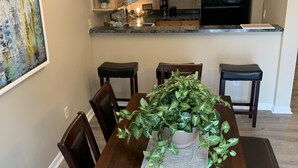 A dining area with a wooden table, chairs, and a central potted plant. - 2 Story Townhouse walk to Atlantic Ave (Delray Beach)