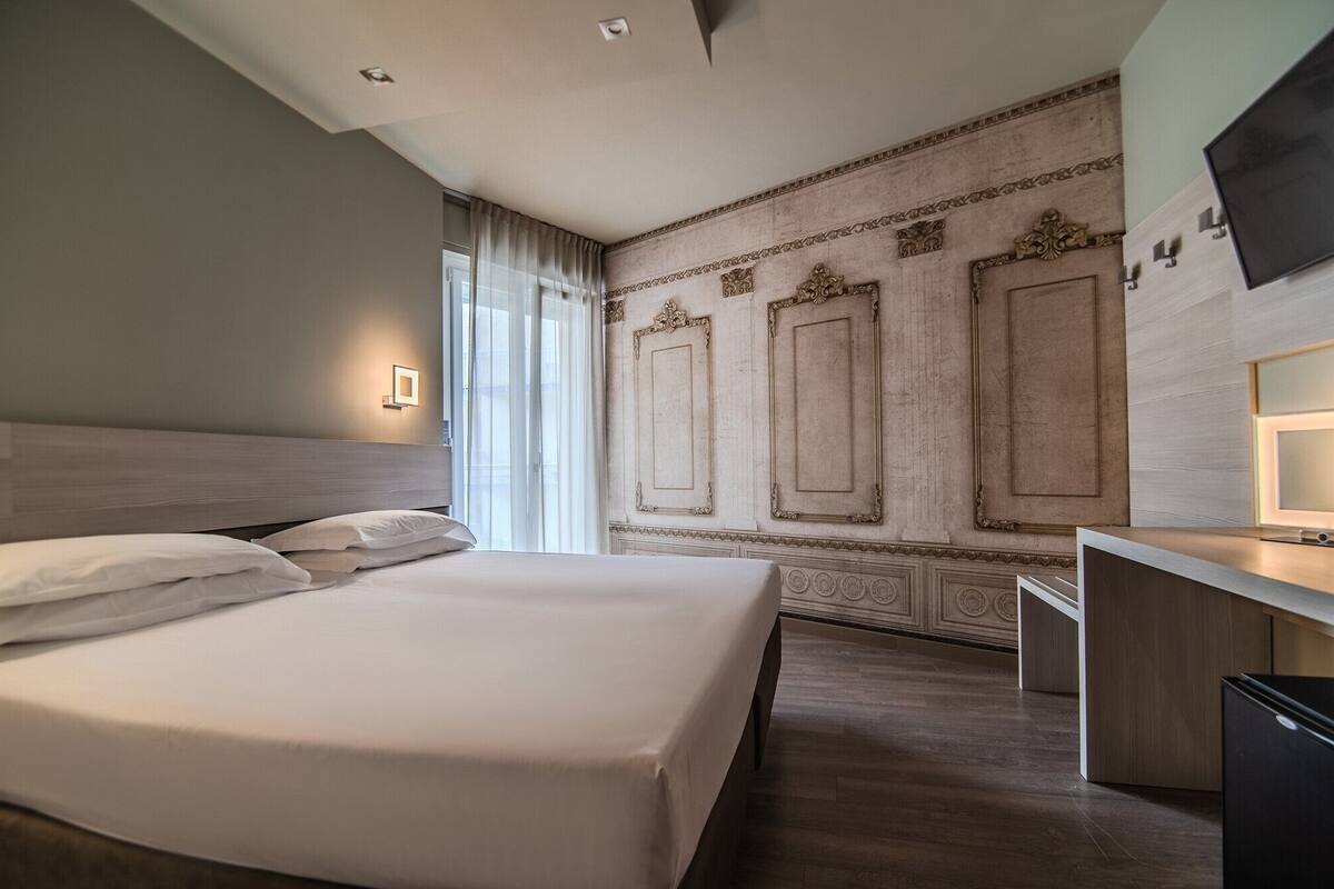 A hotel room with a large bed, a desk, and a TV.