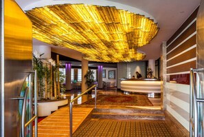 A hotel lobby with a reception desk, a staircase, and a large decorative ceiling. - Cesare Augustus (Jesolo)
