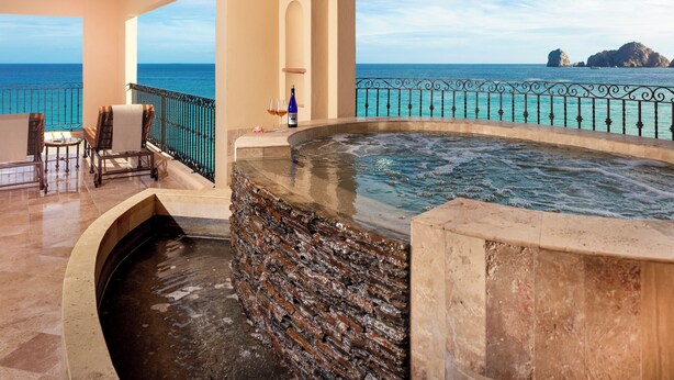 A spa area with a hot tub, seating, and a view of the sea.