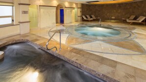 A spa area with a hot tub, a water slide, and lounge chairs.