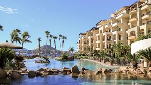 A resort with a pool, palm trees, and a mountain in the background.