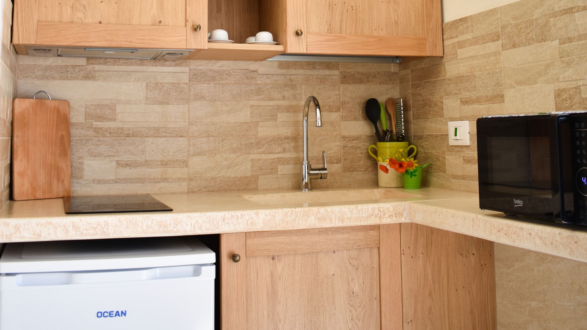 Una cocina con armarios de madera, un lavamanos de acero inoxidable, un microondas y un lavavajillas.