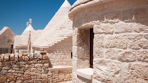 Edifici de pedra tradicional amb una porta arrodonida i un mur de pedra.