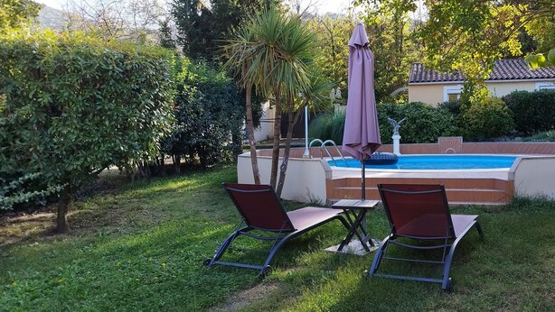 Piscina com duas espreguiçadeiras e um guarda-sol.