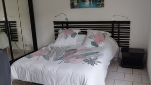 Uma cama bem arrumada com roupa de cama florida, uma cabeceira preta e uma pequena mesa de cabeceira.