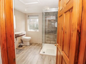 A bathroom with a toilet, shower, and a window. - Greenbank Cottage (Kendal)