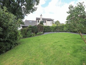 A well-maintained lawn with a hedge, a bench, and a house in the background. - Greenbank Cottage (Kendal)