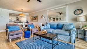Una sala de estar con un sofá, sillones, una mesa de centro y un comedor con mesa y sillas.