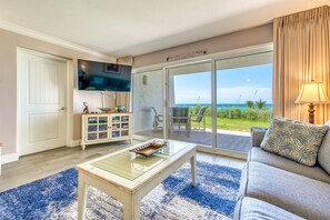 Relax in a comfortable seating area with a sofa and coffee table, perfect for socializing or unwinding. Enjoy ocean views through the sliding glass door.