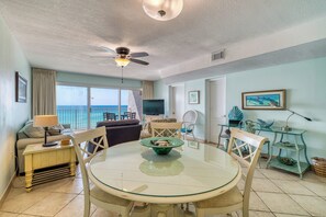 A dining area with a round glass table, chairs, and a ceiling fan. - B405 | Beachfront with Beach Service, Pool, & WiFi (Miramar Beach)