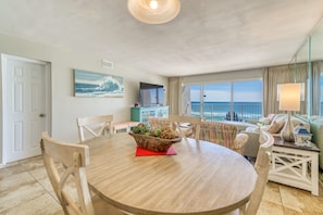 Enjoy meals with a view of the ocean from this dining area, featuring a round table and comfortable seating for four.