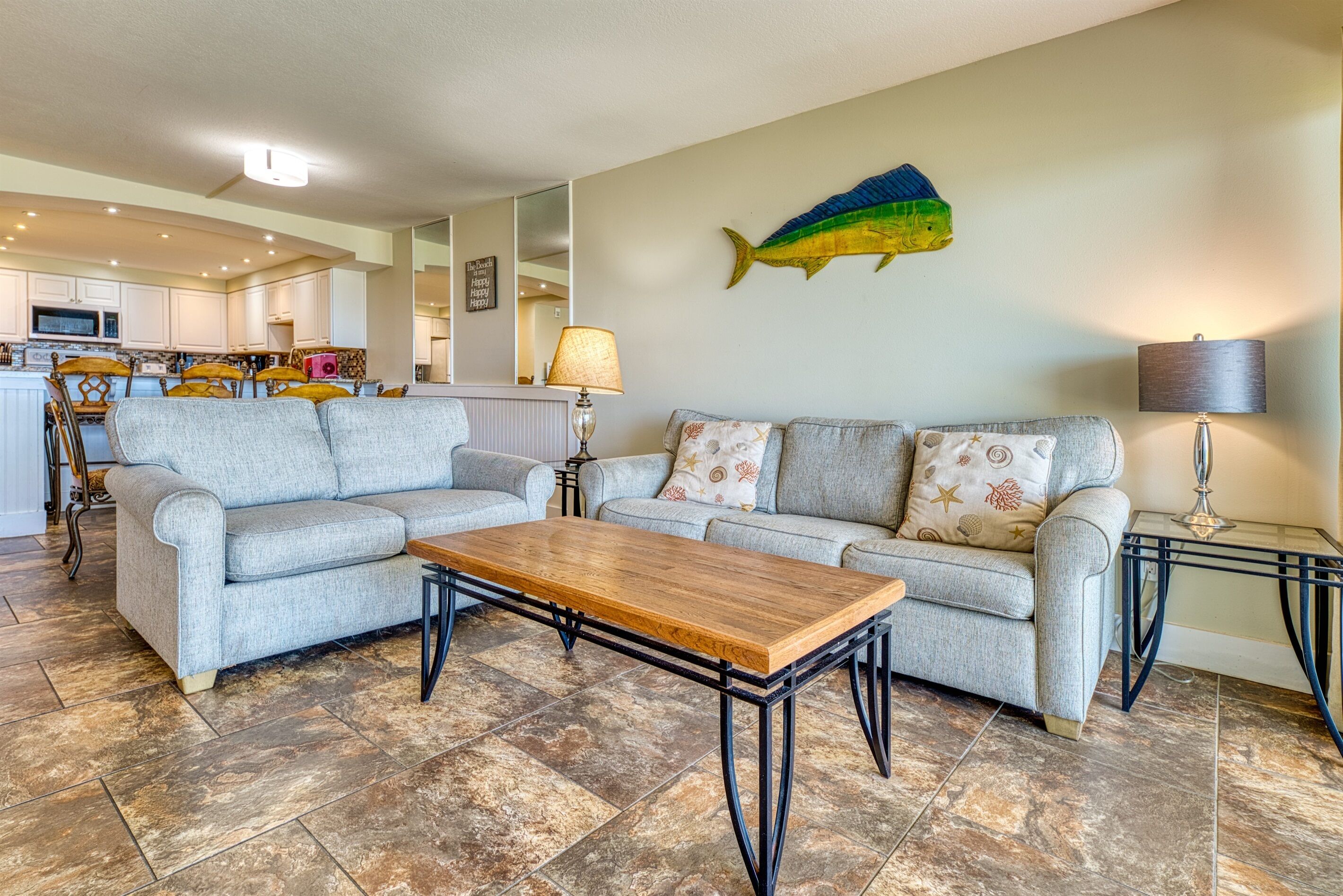 A living room with two grey sofas, a wooden coffee table, and a fish wall art piece.