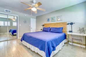 Ein Schlafzimmer mit einem großen Bett, einem Deckenventilator, einer Wanduhr und einem kleinen Tisch mit einer Lampe.