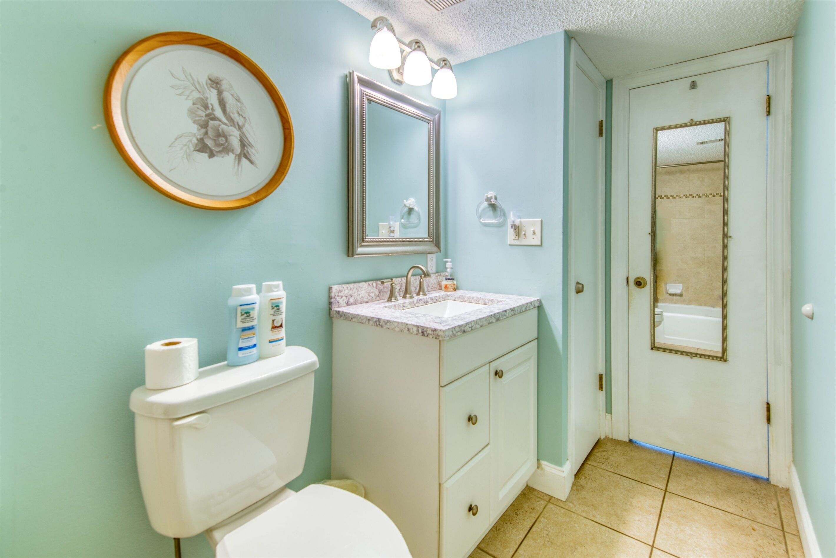 Un bagno con il water, un lavandino, un mobile lavabo e un quadro appeso al muro.