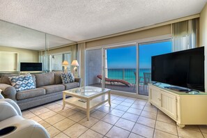 Ein modernes Hotelzimmer mit Balkon, einer Couch, einem Fernseher und einem Glastisch.