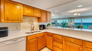 A modern kitchen with wooden cabinets, a dishwasher, and a coffee maker. - D404 | Beachfront with Beach Service, Pool, & WiFi (Miramar Beach)