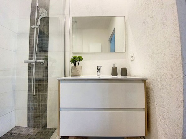 A bathroom with a shower, a sink with a mirror, and a plant on the counter. - Villa Casalilo, piscine privée, à 100m de la plage d`Orient Bay, 2 chambres (Orient Bay)