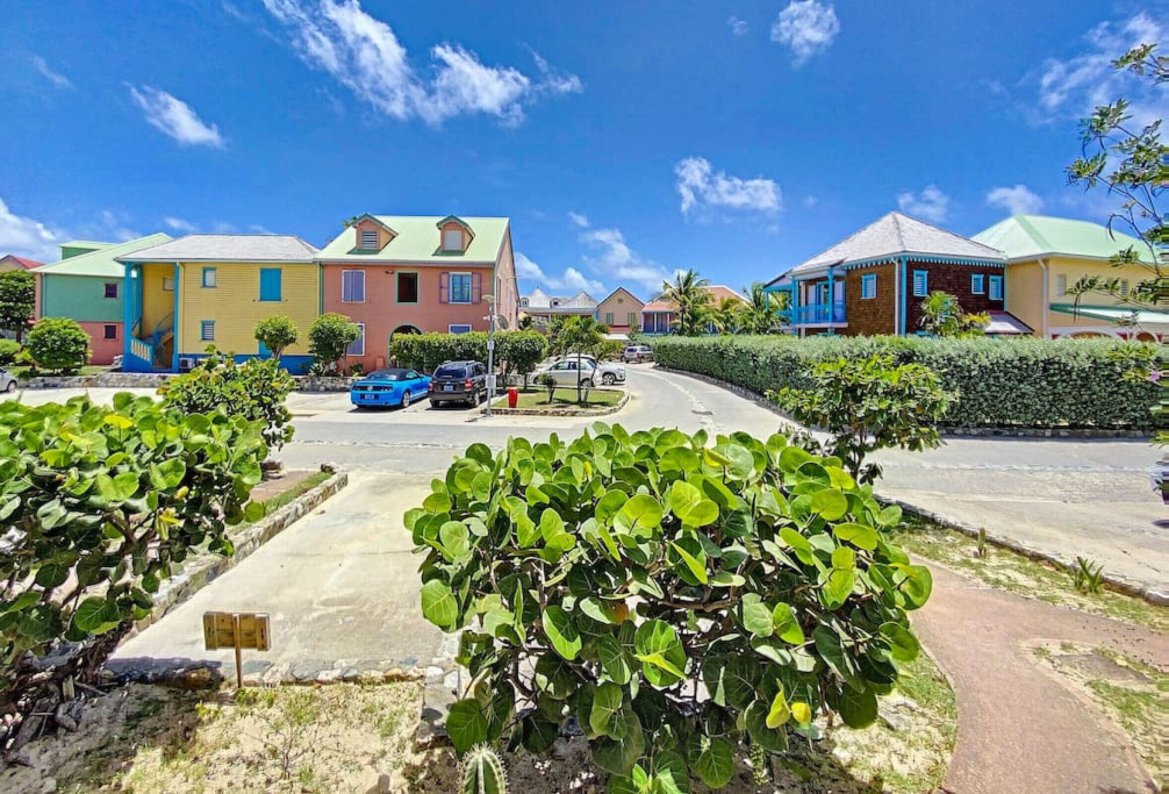 A residential area with colorful houses, a roundabout, and a parking lot.