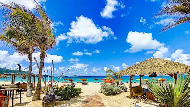 A beach scene with a clear sky, palm trees, a thatched-roof structure, and a barrel labeled 'RAMUM ISLAND'.