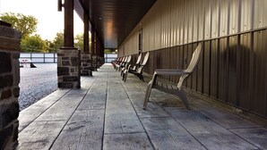 A covered outdoor seating area with stone pillars and a row of chairs.