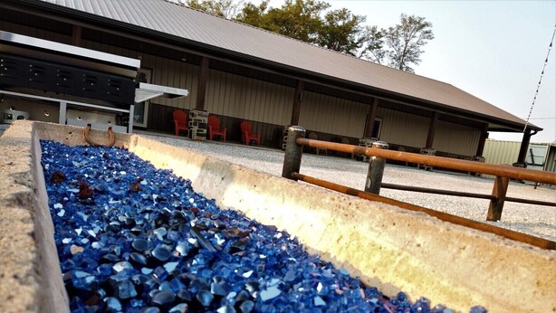 A gravel bed with blue crystals, a metal structure, and a building with a metal roof.