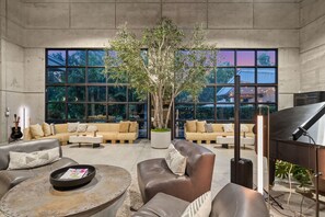 A spacious living area with leather sofas, a coffee table, and a grand piano.