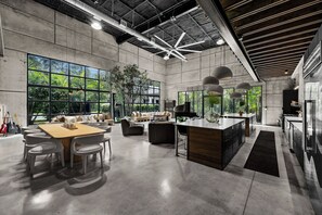 A spacious open-plan living area with a kitchen, large windows, and a ceiling fan.