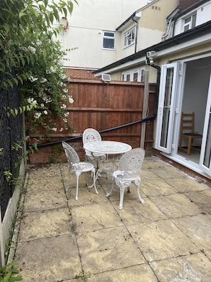 A patio with a white metal table and chairs, a wooden fence, and a sliding glass door. - 2 En-suite Bedrooms Flat in Kidlington ,oxford (Kidlington)