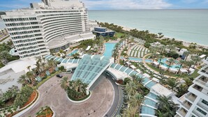 Ein Resort mit großzügiger Poolanlage, einer gebogenen Glasarchitektur und Blick auf den Ozean.