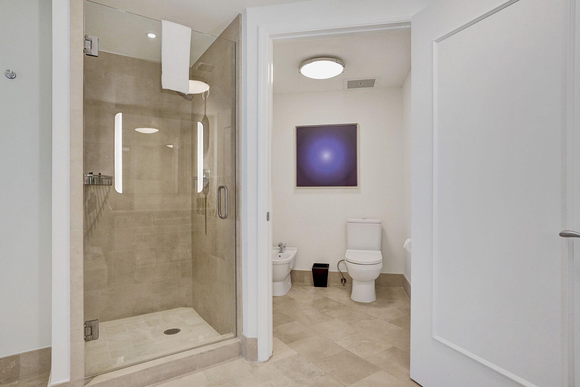 A modern bathroom with a glass-enclosed shower, a toilet, and a sink.