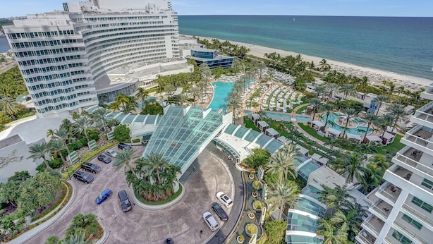 Ein Resort mit mehreren Schwimmbecken, einem großen Hotelgebäude und einem Strand.