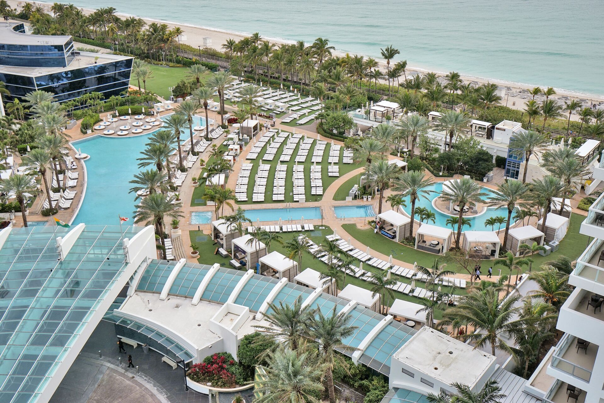 Un resort con varias piscinas, tumbonas y palmeras.