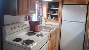 Una cocina compacta con gabinetes de madera, una estufa blanca, un lavamanos y un refrigerador.