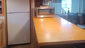 Una cocina con armarios de madera, un refrigerador blanco, un microondas y luces colgantes.