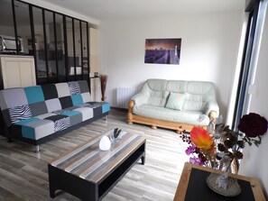 A living room with a sofa, a coffee table, and a decorative vase with flowers. - The Swallow House (Nauroy)