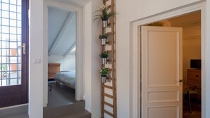 A staircase with a wooden ladder, white walls, and potted plants.