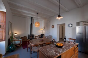 Une cuisine chaleureuse avec une table à manger en bois, un îlot en marbre et un réfrigérateur encastré.