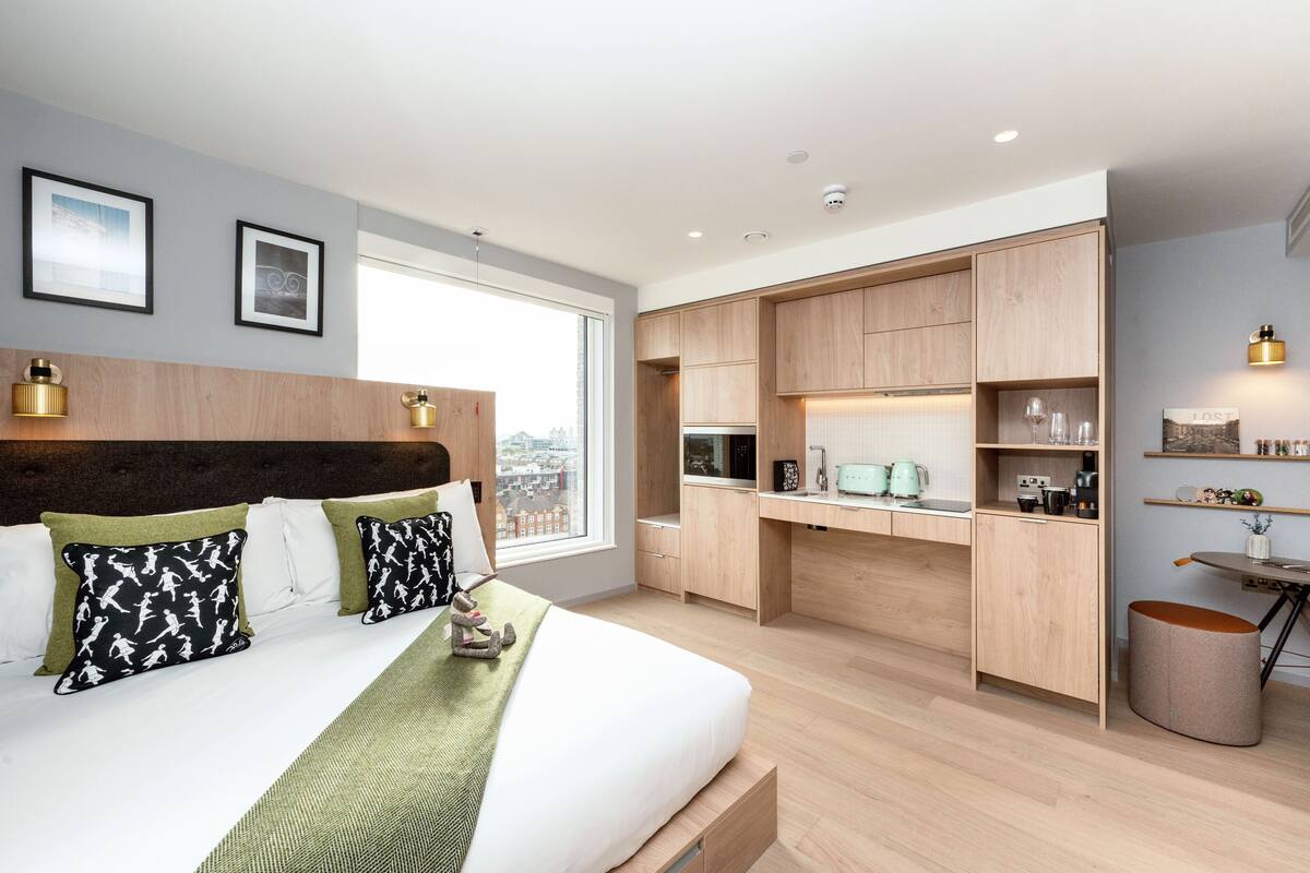 Une chambre moderne avec un grand lit, un bureau intégré et une vue sur la ville.