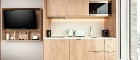 A modern kitchen with wooden cabinets, a built-in microwave, and a flat-screen TV.