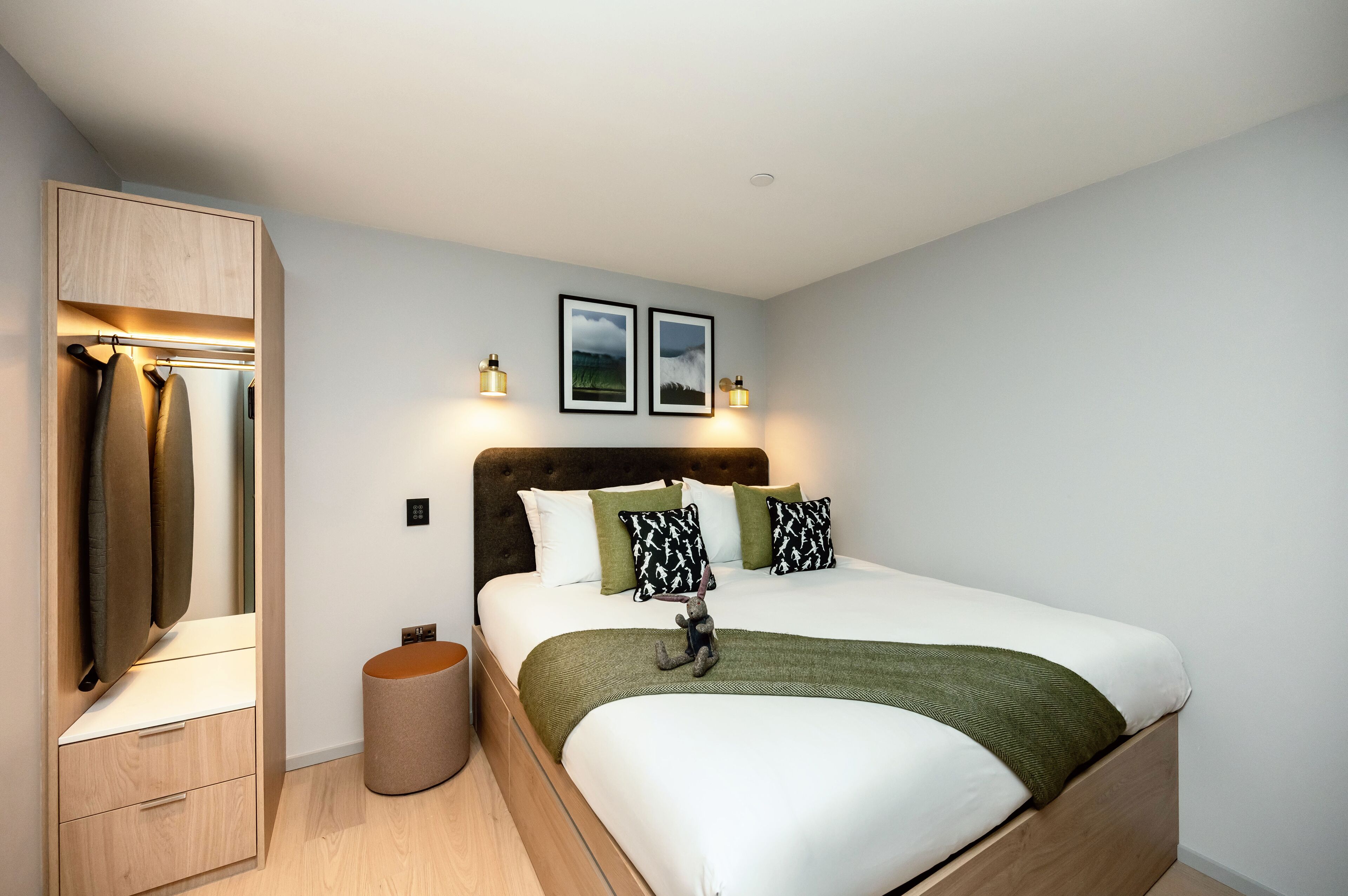 A bedroom with a bed, a wardrobe, a mirror, and two wall-mounted lights.