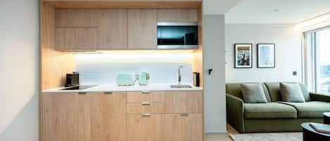 Une cuisine moderne avec des meubles en bois, un four à micro-ondes encastré et un plan de travail de couleur claire.