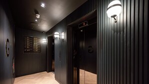 A modern elevator with a digital display showing the floor number, flanked by vertical wooden panels and recessed lighting.